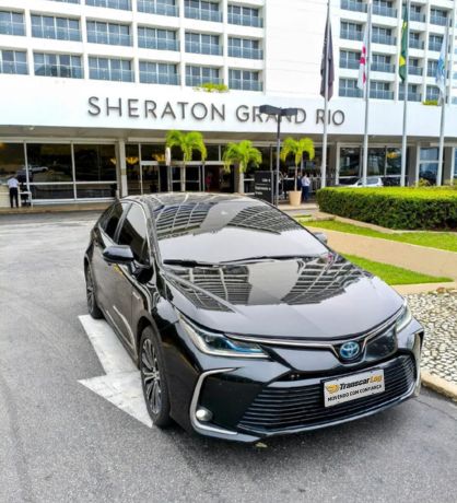 Carro Corolla preto ao fundo hotel